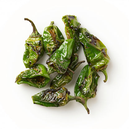 Gegrillte Pimientos de Padrón mit leicht angeschwärzter, runzliger Schale, glänzend von Öl und grobem Salz, frisch vom Grill serviert.